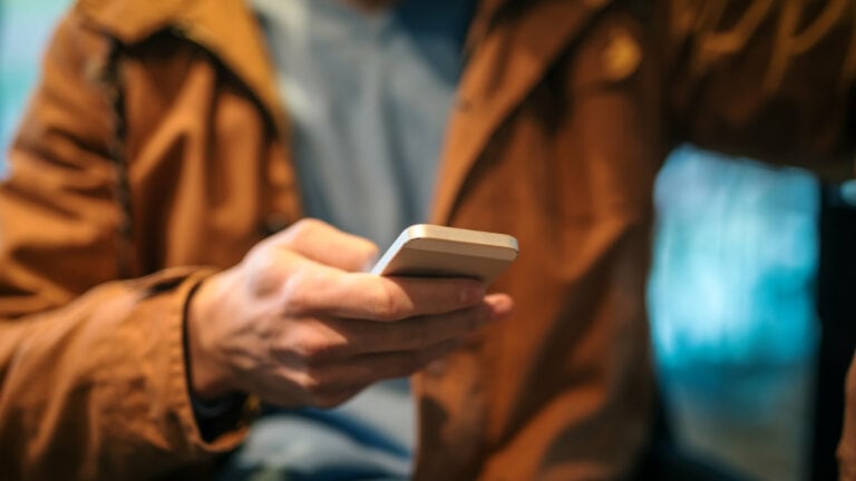 the image depicts an individual actively interacting with their mobile device, symbolizing the modern digital consumer's active engagement in creating and sharing User-Generated Content (UGC) through their personal devices
