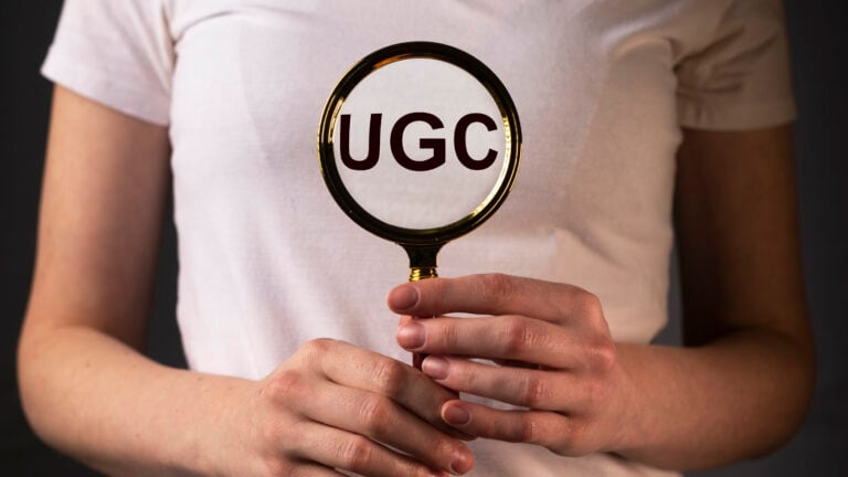 Person examining UGC text through a magnifying glass, symbolizing the exploration of User-Generated Content in digital marketing
